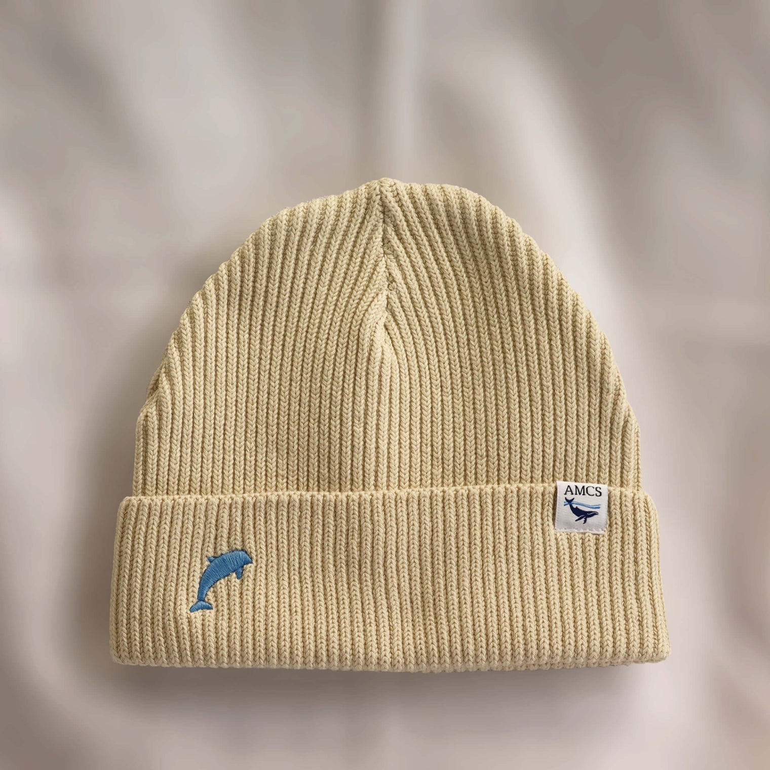 Ocean Icons organic cotton, beige beanie embroidered with a dolphin in blue thread.