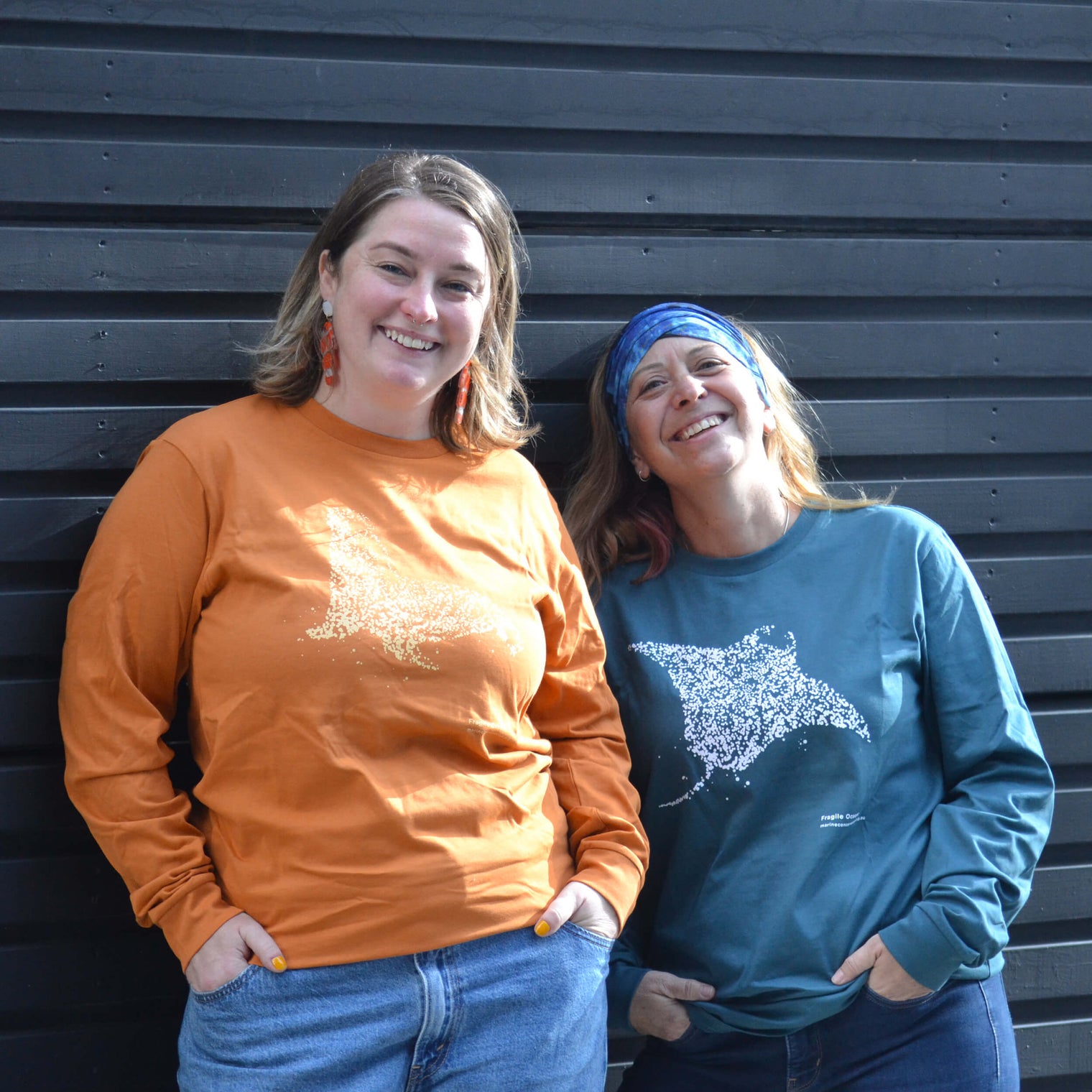 AMCS team wearing Fragile Oceans organic cotton, long sleeve, orange t-shirt with seal print and teal t-shirt with manta ray print.