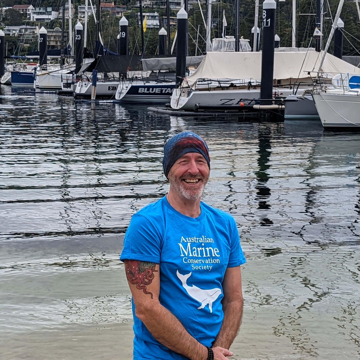 AMCS team member wearing Headsox buff with a boat marina and yachts in the background.