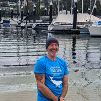 AMCS team member wearing Headsox buff with a boat marina and yachts in the background.