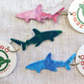 Purple, blue and green shark shaped keyrings made with recycled plastic milk bottle lids.