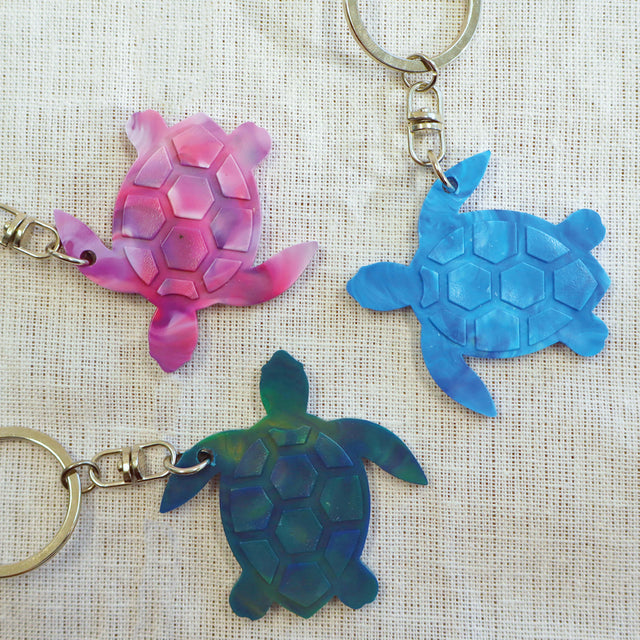 Purple, blue and green turtle shaped keyrings made with recycled plastic milk bottle lids.