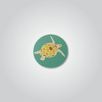 Lapel pin of a green sea turtle by Red Parka. 