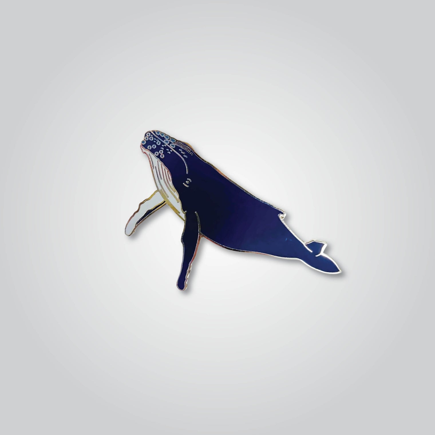 Lapel pin of a humpback whale by Red Parka. 
