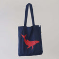 Ocean Love denim blue tote bag with a pink humpback whale print, made from recycled materials.