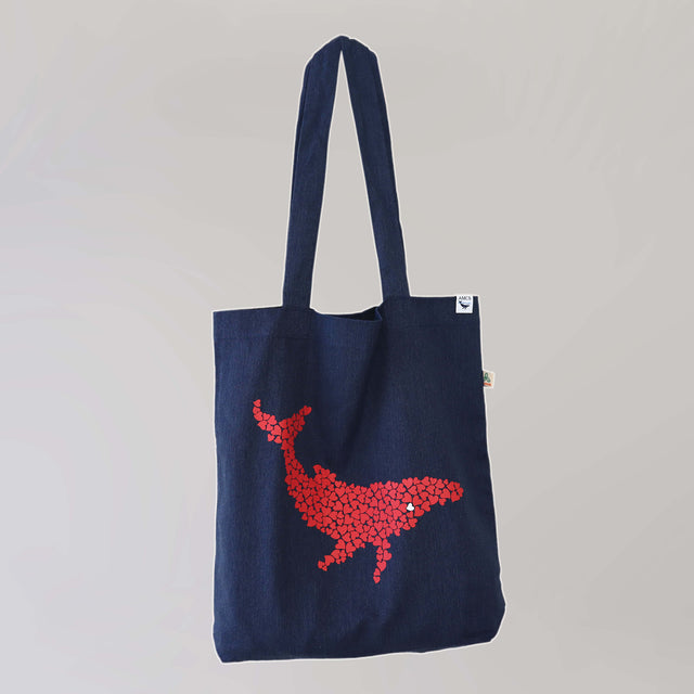 Ocean Love denim blue tote bag with a pink humpback whale print, made from recycled materials.